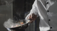 Cocinero sostiene una sartén mientras cocina